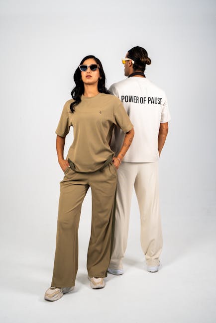 Stylish duo in casual attire, sunglasses, posing against a neutral backdrop.