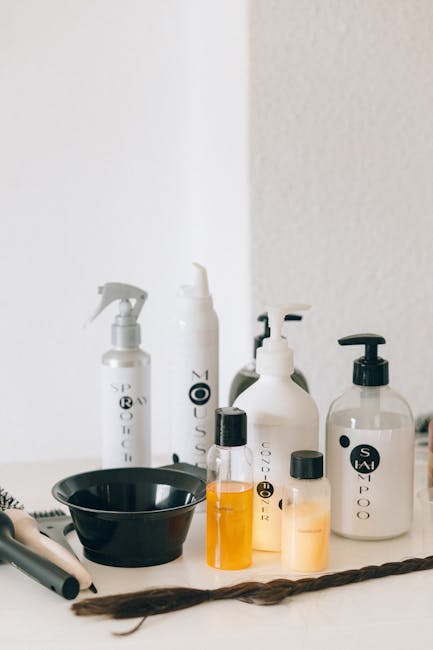 A collection of haircare bottles on a white counter with styling tools.
